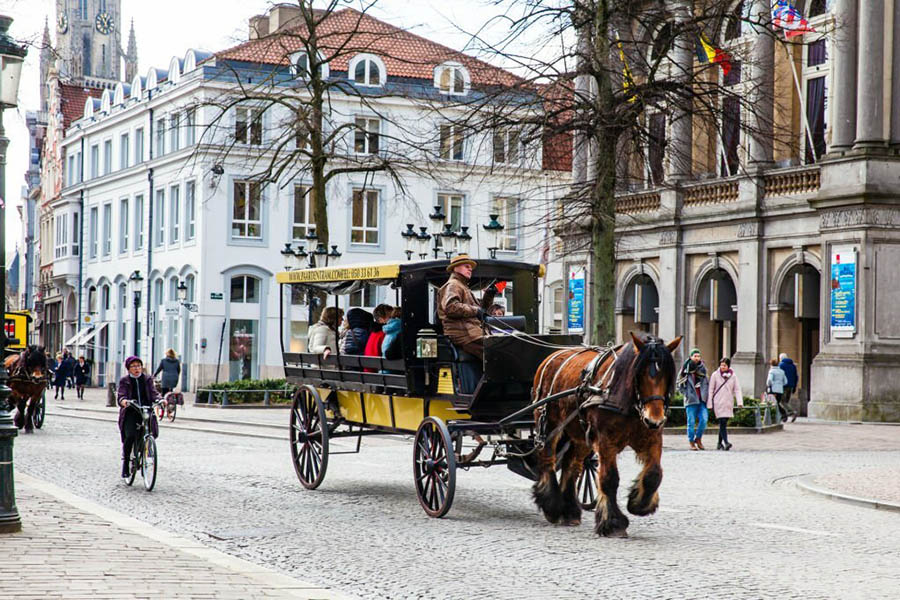 PARIS, FRANCE - MARCH, 2018: People touring around the beautiful Bruges town on a carriage pulled by a horse