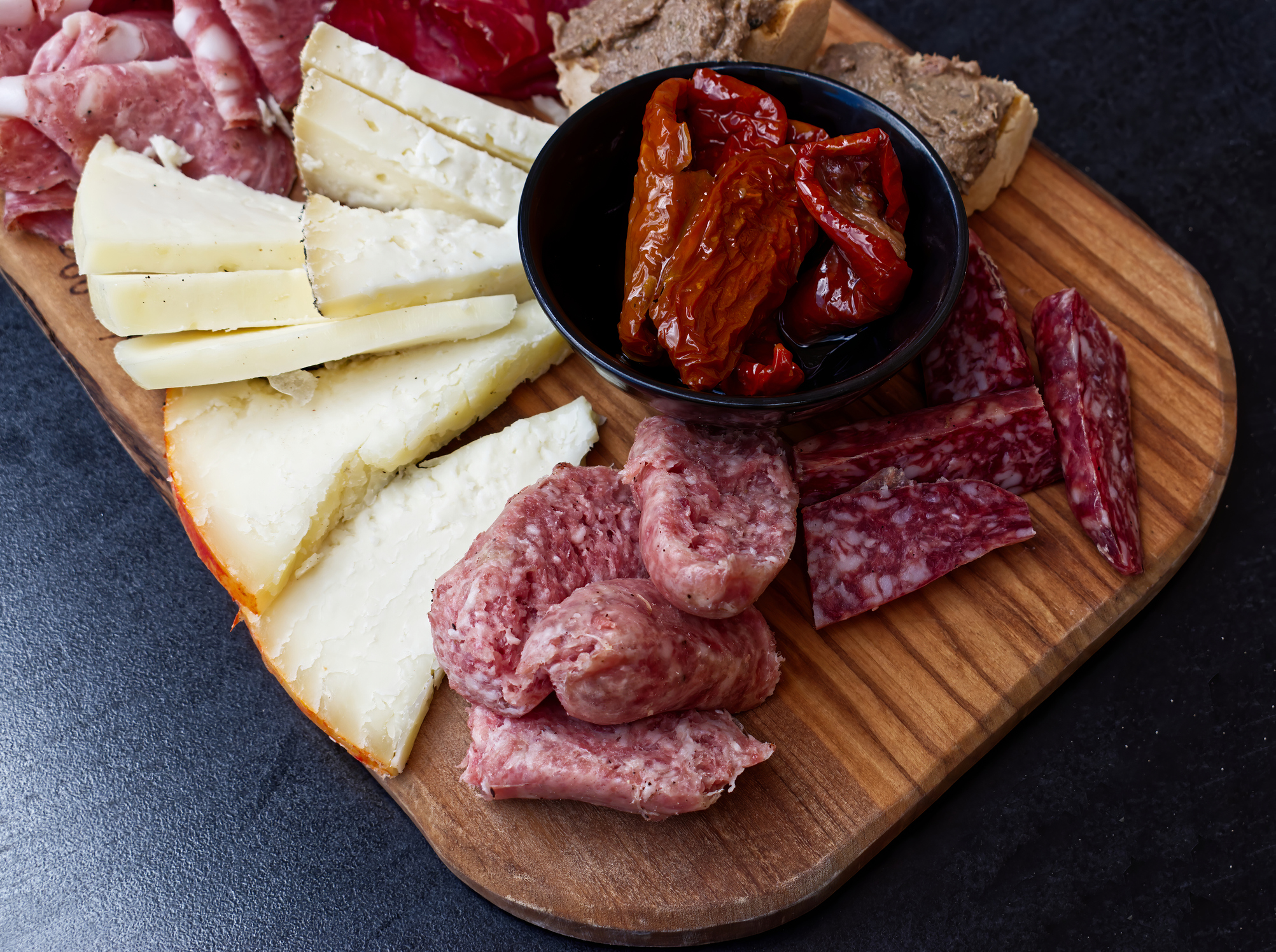 Rustic Tuscan tray with typical products: prosciutto (ham), brawn, finocchiona, crostini, salami, tuscan chilli and sliced pecorino cheese. San Gimignano, Italy